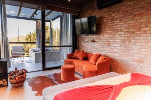 a living room with orange furniture and a brick wall at Cabana Morada nas Nuvens in Pinto Bandeira