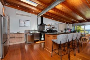 a kitchen with wooden ceilings and a bar with stools at Vince's Landing - Stunning Big Private Waterfront Cottage in Erowal Bay