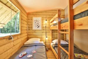 two bunk beds in a wooden cabin with a window at Camping Le Petit Rocher in Longeville-sur-Mer +80 photos
