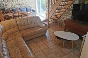 ein Wohnzimmer mit einer Ledercouch und einem Tisch in der Unterkunft Les Gites de Louisette Le 974 in Ébreuil