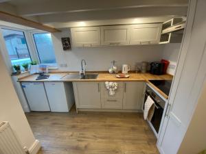 une petite cuisine avec des armoires blanches et un évier dans l'établissement Seatons Hidden Gem Charming Holiday Cottage with Garden, à Sigglesthorne