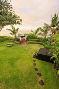 a lawn with a picnic table and the ocean in the background at The Emerald House II apts in Waialua