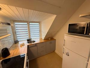 a small kitchen with a refrigerator and a sink at Hel ændre men hyggelig lejlighed in Sønderborg