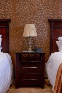 a table with a lamp on it next to two beds at Ekupholeni Garden Villas in Manzini