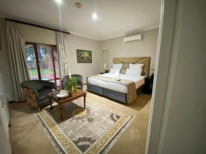 a bedroom with a bed and a chair and a table at Kloofyard Guesthouse in Pretoria