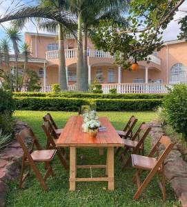 a wooden table and chairs in front of a house at Ekupholeni Garden Villas in Manzini