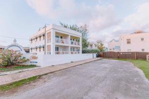 ein weißes Haus mit einem Zaun und einer Einfahrt in der Unterkunft Ocean Bliss Apt 9 in Christchurch