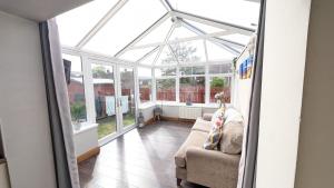 a conservatory with a couch in a room with windows at Sydenham Serenity: Bright Home with Conservatory in Belfast
