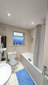 a bathroom with a tub and a toilet and a sink at Sydenham Serenity: Bright Home with Conservatory in Belfast