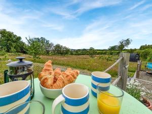a table with a bowl of croissants and cups of orange juice at The Owl Pod - Uk50070 in Welshpool