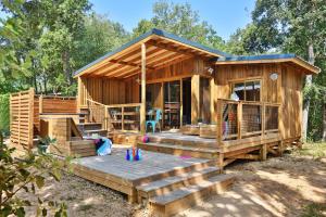 a wooden cabin with a deck in the woods at Camping Le Petit Rocher in Longeville-sur-Mer
