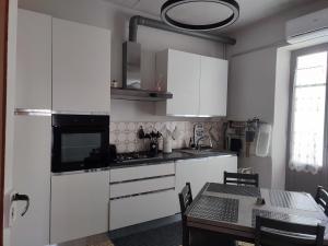 a kitchen with white cabinets and a dining table at L'angolo in Biella