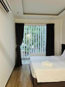 ein Schlafzimmer mit einem Bett und einem großen Fenster in der Unterkunft Full House Hotel Apartment in Đà Nẵng