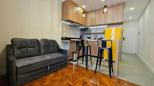 a living room with a couch and a kitchen at Studio reformado e bem equipado in Campinas