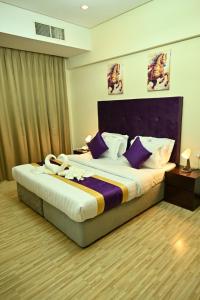 a bedroom with a large bed with purple pillows at Aspire Tower in Manama
