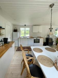 a kitchen with white cabinets and a table and chairs at Sommerhus Med Sauna Ved Udsholt Strand in Udsholt Sand