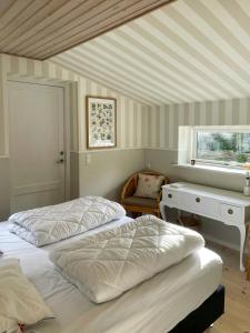 a bedroom with two beds and a desk and a window at Sommerhus Med Sauna Ved Udsholt Strand in Udsholt Sand