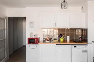 a kitchen with white cabinets and a red microwave at Ô Cocon Paisible - WiFi, Calme, Smart TV, Parking - A 2min du Campus TBS in Quint-Fonsegrives +8 photos