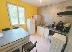 a kitchen with a refrigerator and a table and chairs at Gîte du Vert Galant in Brantôme