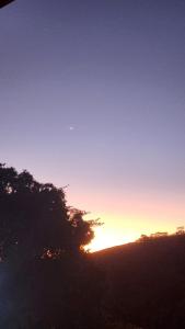 una puesta de sol en el cielo con un árbol en primer plano en Refúgios SUNSET Serra Fluminense, en Areal