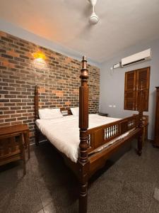 a bedroom with a bed and a brick wall at Greens Heritage Resort with Swimming Pool in Auroville