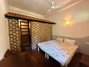 a bedroom with a bed in front of a brick wall at Greens Heritage Resort with Swimming Pool in Auroville