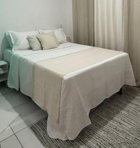 Una cama grande con sábanas blancas y almohadas. en Anny Guest, en Camassari