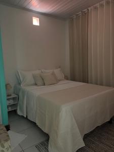 Un dormitorio con una cama grande con sábanas blancas. en Anny Guest, en Camassari