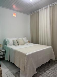 Un dormitorio con una cama grande con sábanas blancas. en Anny Guest, en Camassari