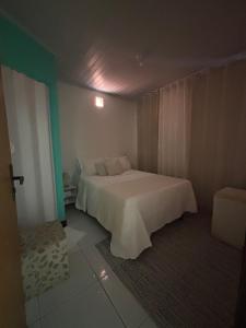 Un dormitorio con una cama blanca en una habitación. en Anny Guest, en Camassari