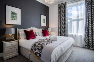 a bedroom with a bed with red pillows and a window at The Helaina Apartments in Scarborough