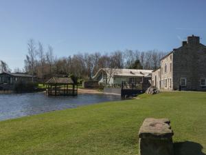 a building next to a river with a gazebo at Bluebell Lodge in Carnforth