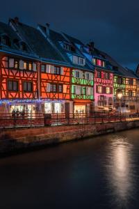 a lit up building next to the water at night at Le Cathedral View Colmar - Centre Historique - Parking privé gratuit in Colmar