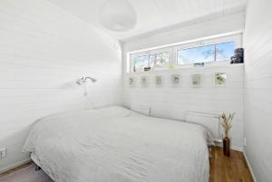a white bedroom with a bed and a window at Modern Archipelago Cabin With Hot Tub On Timrarön in Vadholma +11 photos