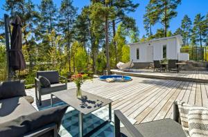 a backyard with a wooden deck and a white shed at Modern Archipelago Cabin With Hot Tub On Timrarön in Vadholma