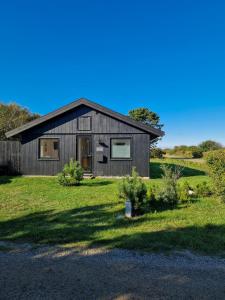 a wooden house with a grassy yard at Renovated Beach House With Ocean View in Tjørneholm