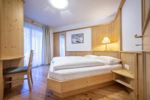 Un dormitorio con una cama grande y una silla. en Marienstern Apartments, en Santa Cristina Valgardena