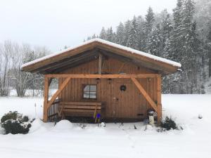 een kleine hut met een met sneeuw bedekt dak in een veld bij Ferienhaus In Röhrnbach Mit Grill Und Terrasse in Röhrnbach