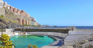 une grande piscine d'eau devant un bâtiment dans l'établissement Dúplex de Lujo Frente al Mar Terraza en Radazul, à Radazul