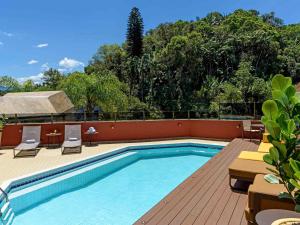 a swimming pool with a deck and chairs and trees at Apartamento no Hotel Prinz in Joinville