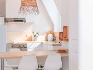 eine Küche mit einem Holztisch und weißen Stühlen in der Unterkunft Appartement lumineux au centre-ville du Touquet - FR-1-821-28 in Le Touquet-Paris-Plage