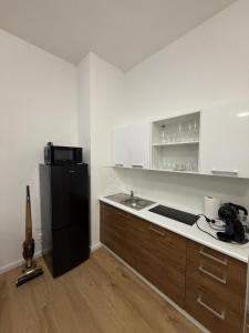 eine Küche mit einem schwarzen Kühlschrank und einer Spüle in der Unterkunft The Blue Church Family Apartment Old Town Self Check-in 6 guest in Bratislava