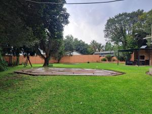 Un patio con césped y un parque con un árbol. en Buccleuch Home, en Sandton
