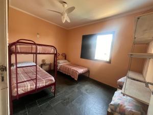 a room with two bunk beds and a flat screen tv at Refúgio em Ubatuba - Perto de tudo in Ubatuba