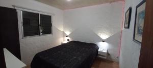 a bedroom with a black bed and two lights at Kasty in Piriápolis