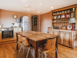 a kitchen with a wooden table and chairs at The Shearing Shed in Peasmarsh