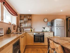 a kitchen with a table and a refrigerator at The Shearing Shed in Peasmarsh