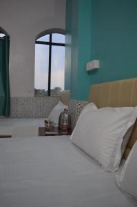 a bedroom with a bed with white pillows and a window at Aakarsh Hill View Hotel in Rājgīr