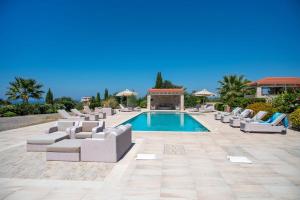 a patio with lounge chairs and a swimming pool at Villa Elia, By Hellocrete in Astérion