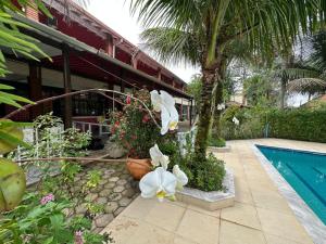 a resort with a swimming pool and some flowers at Pousada CASA BELA mar in Itanhaém